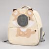 Cream pet backpack carrier with a round mesh porthole and an applique cat face on a plain background.