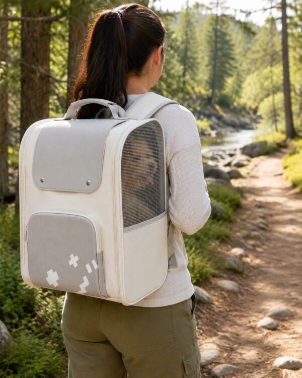 A woman walks a forest path wearing the white pet backpack carrier.