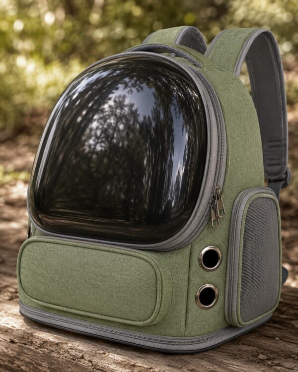 The olive pet backpack with its clear dome sits on a wooden bench in the woods.