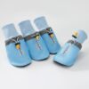 Set of four light blue dog paw boots with cinch tops, on a plain background.