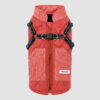 Coral quilted dog winter coat on light grey, showing the back zip, harness straps and two corduroy pockets.