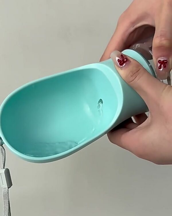 Hand holding the bottle on its side with a thumb on the button, aqua scoop turned up to fill