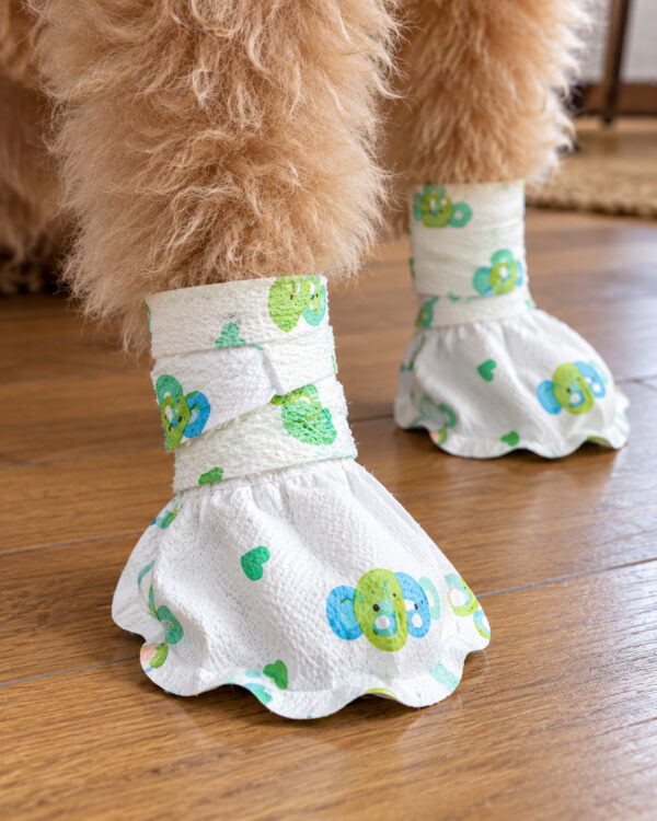 A close view shows printed soft wraps around a poodle’s lower legs above the paw pockets.